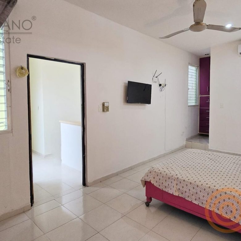 Recámara con cama, TV y ventana, con baño al fondo
