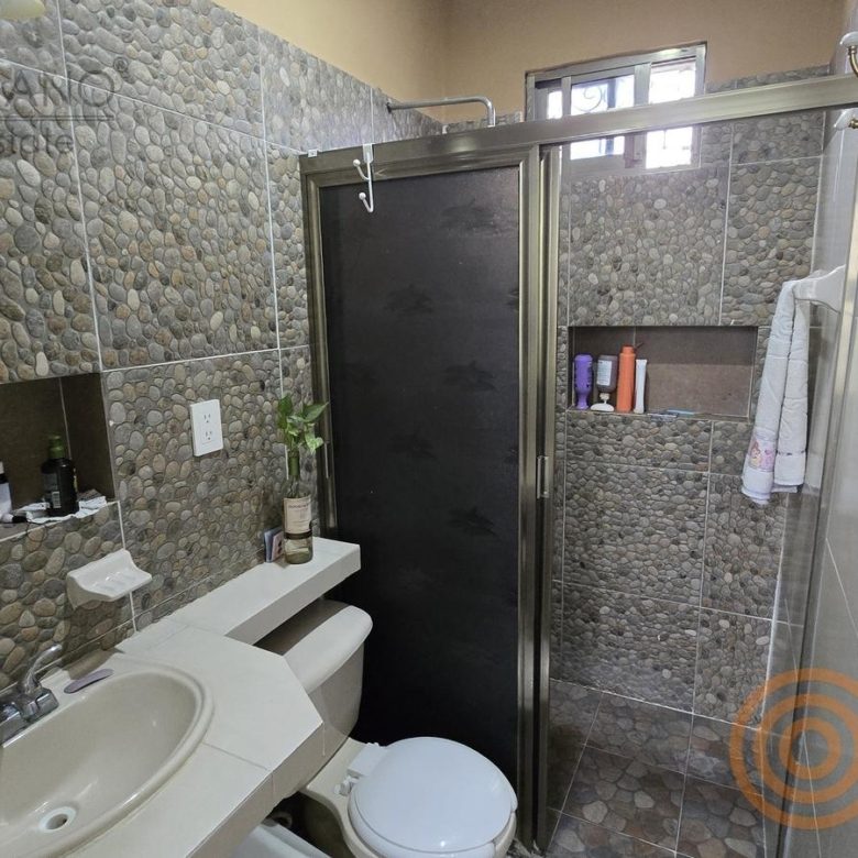 Baño con muro de piedra de río y regadera de cristal