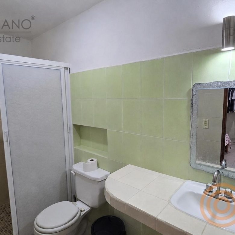 Baño con regadera y lavabo en azulejo verde