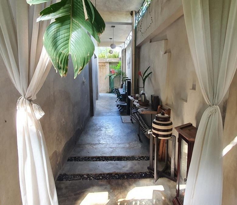 Pasillo con plantas y cortinas hacia las habitaciones