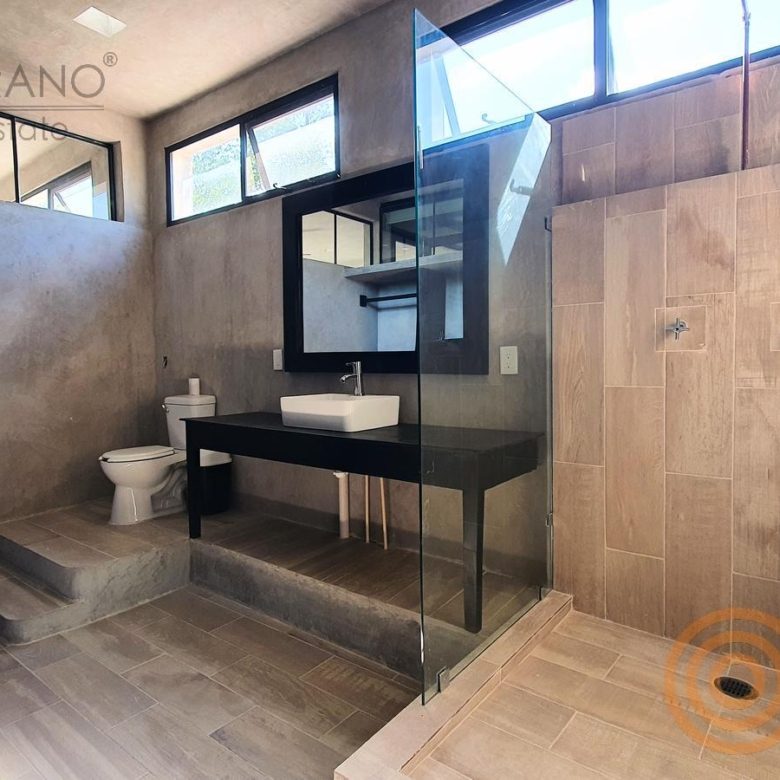Baño con regadera revestida de madera y lavabo negro
