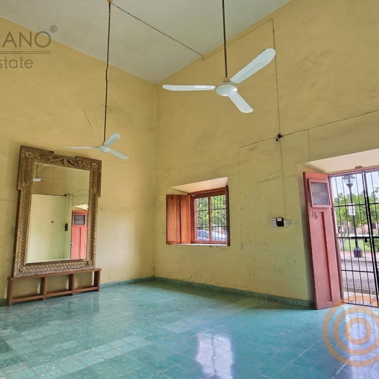 Sala amplia con espejo antiguo, ventilador y piso de pasta turquesa