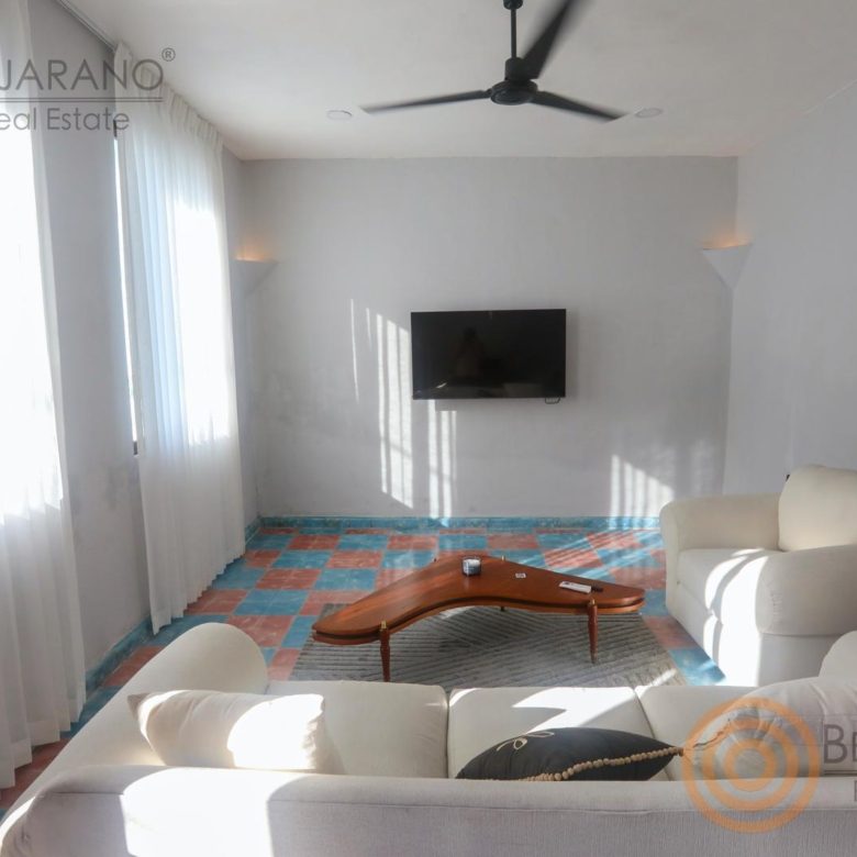 Sala con sillones blancos, TV y ventilador de techo