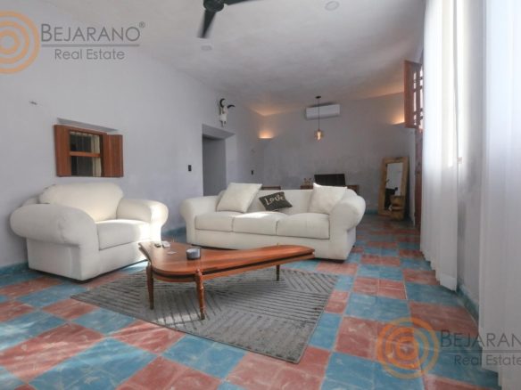Sala con piso de mosaico de colores y sillones blancos