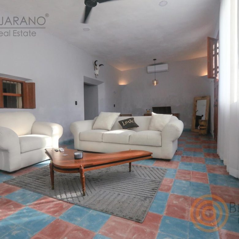 Sala con piso de mosaico de colores y sillones blancos
