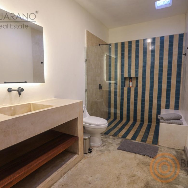 Baño con regadera de azulejo azul y lavabo de concreto