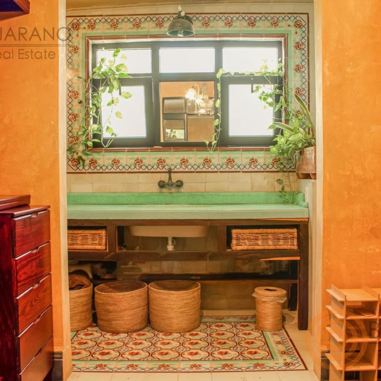 Baño con lavabo verde, ventana y marco de azulejo decorado