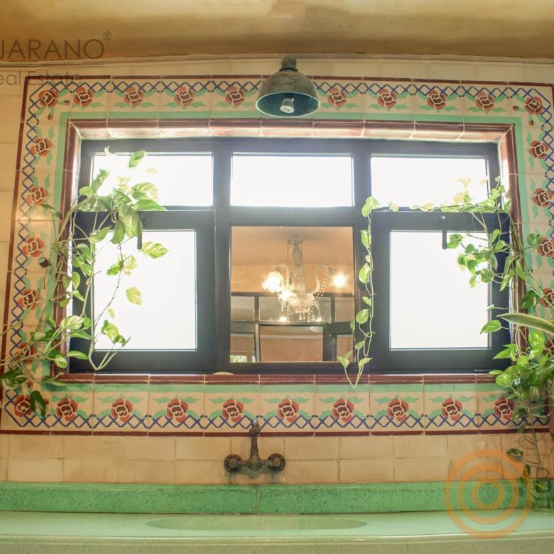 Ventana con marco de azulejo decorado sobre el lavabo