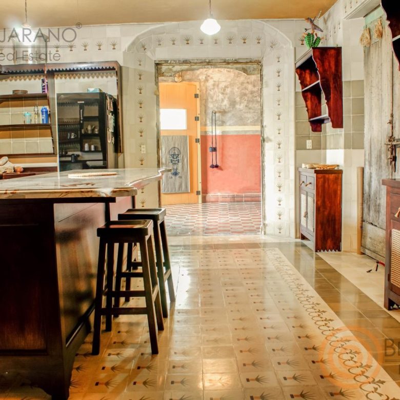 Cocina con isla de granito, bancos y piso de mosaico