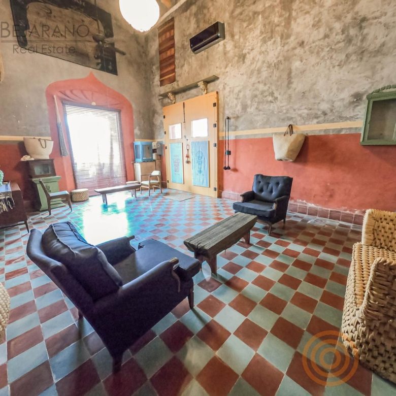 Sala amplia con piso de mosaico y sillones de ratán
