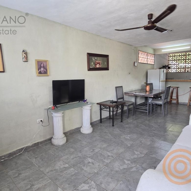 Sala-comedor amplia con sillón blanco, TV y ventilador de techo