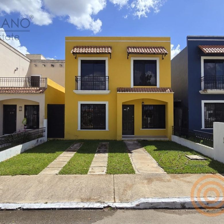 Fachada amarilla de la casa de dos pisos con cielo azul