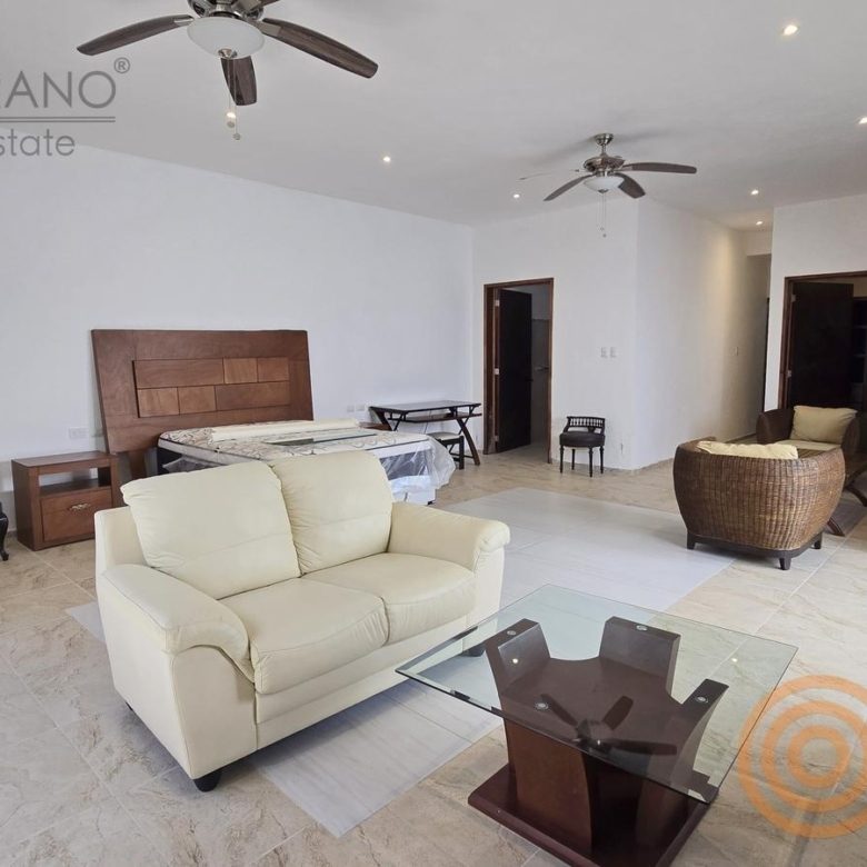 Recámara principal con sillones, cama y ventilador de techo