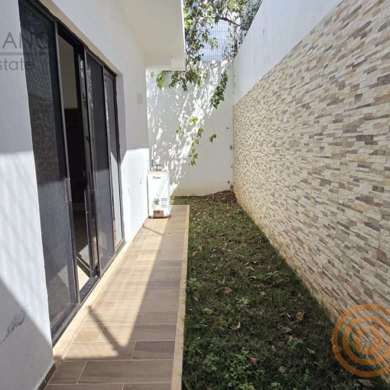 Patio lateral con muro de piedra y pasto