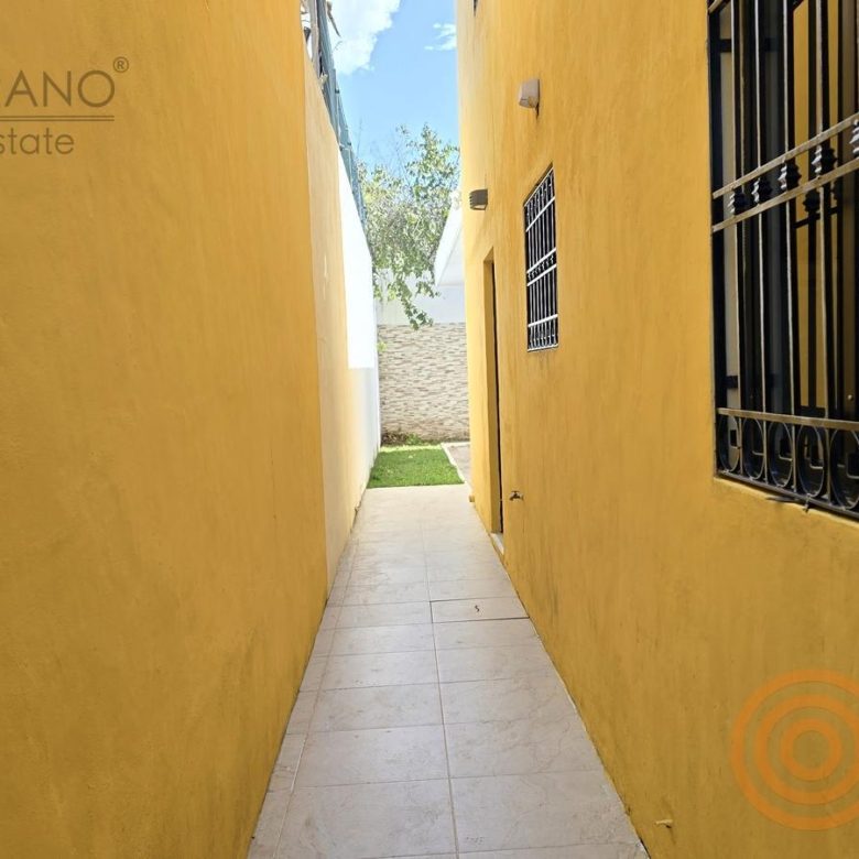 Pasillo lateral con muro amarillo y reja