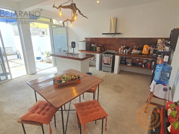 Cocina-comedor con isla de madera y ventanales al patio