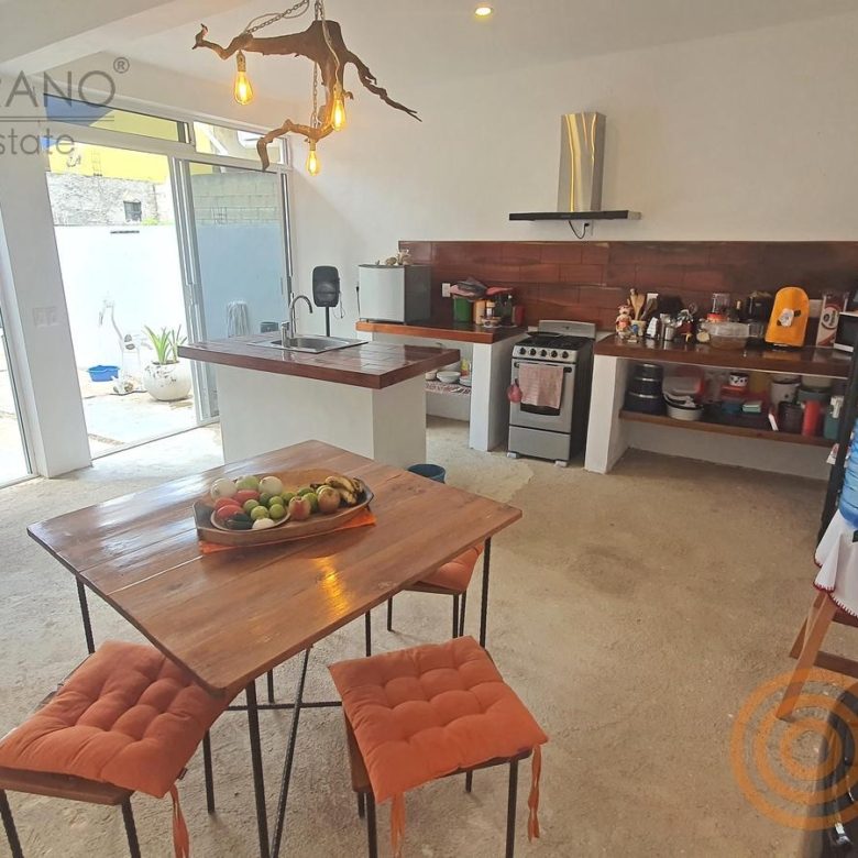Cocina-comedor con isla de madera y ventanales al patio