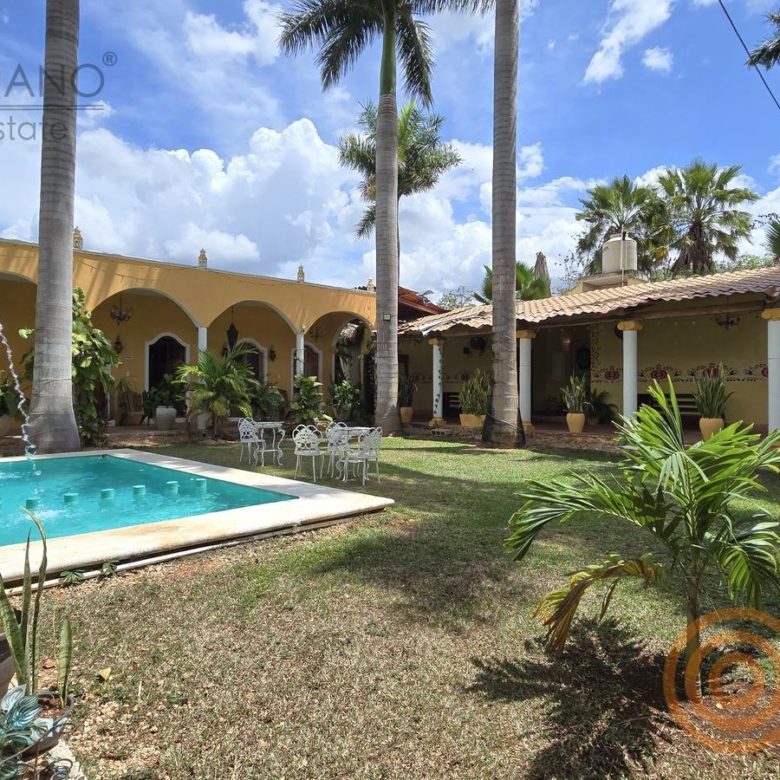 Alberca rodeada de jardín y arcos amarillos