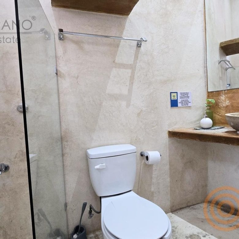 Baño con lavabo de piedra y regadera en el hotel de Sisal