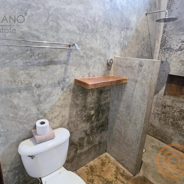 Baño con regadera de concreto pulido en el hotel