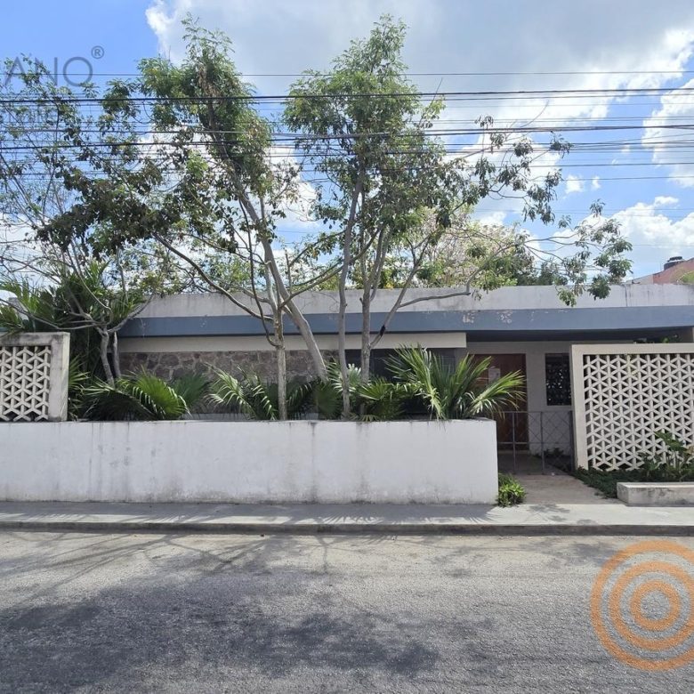 Fachada de la oficina con celosía y muro de piedra en el barrio de San Juan