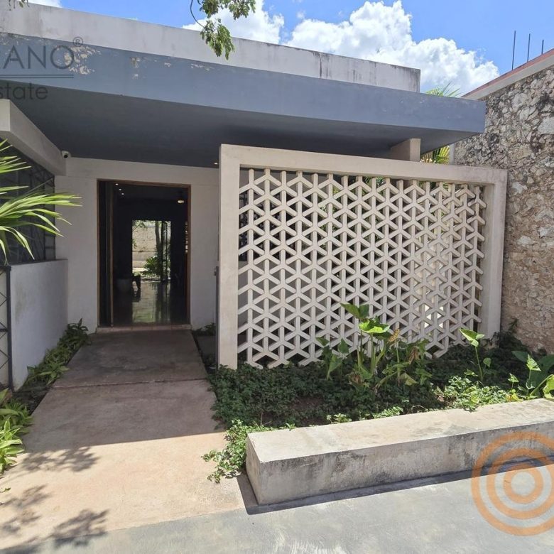 Entrada de la oficina con celosía blanca y plantas