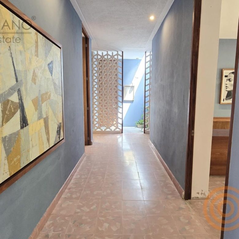 Pasillo con obra de arte y celosía hacia los despachos