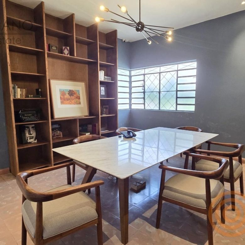 Sala de juntas con mesa blanca y librero de madera