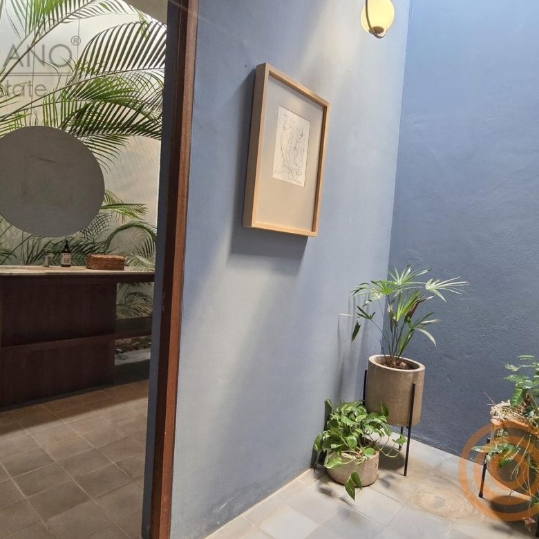 Baño de clientes con lavabo de madera entre plantas