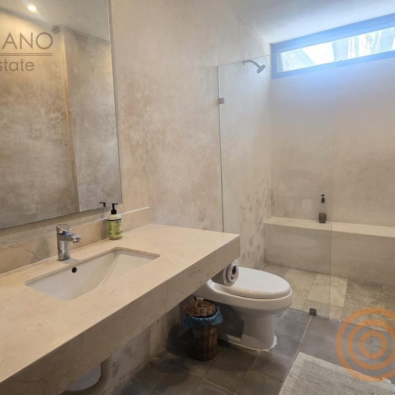 Baño con lavabo, espejo y regadera de una habitación