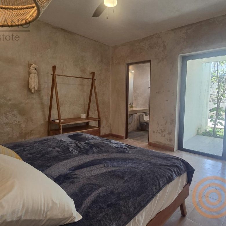 Habitación amueblada con cama, colgador de madera y puerta al jardín