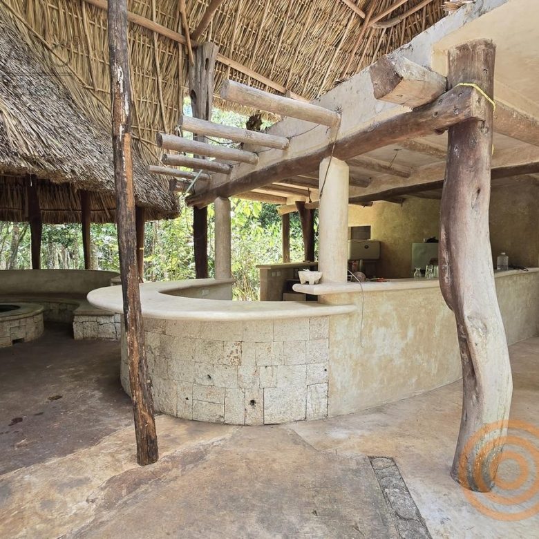 Interior de la palapa principal con barra de piedra y áreas sociales