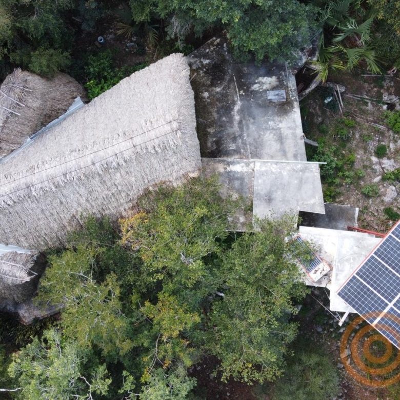 Vista aérea de la palapa y un panel solar entre la selva