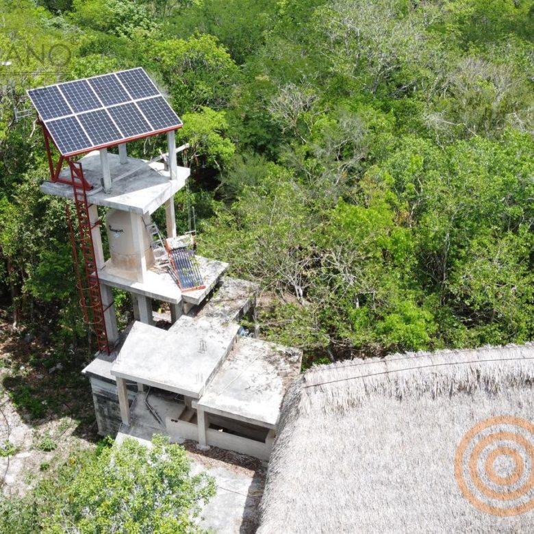 Panel solar y equipo de bombeo junto al cenote entre la vegetación