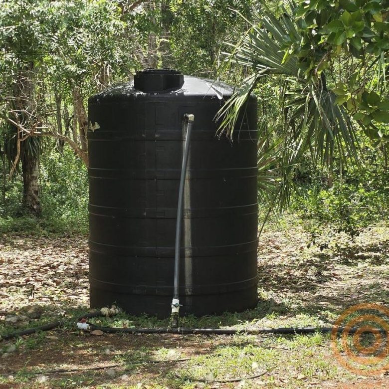 Tanque negro de almacenamiento de agua en el huerto