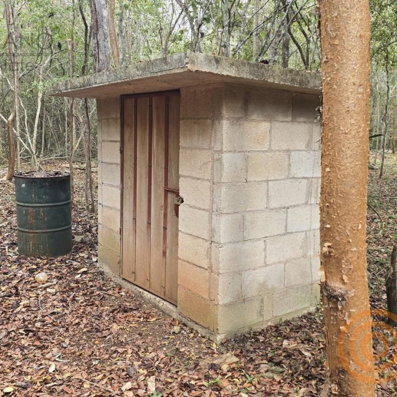 Cuarto de servicio de block junto a un tambo de agua