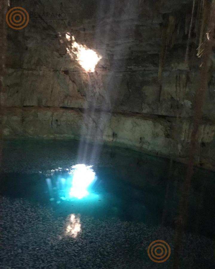 Cenote con rayo de luz sobre el agua turquesa, en un rancho cerca de Valladolid