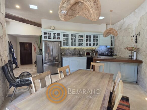 Cocina con comedor de madera y muro de piedra en Valladolid