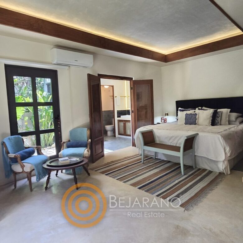 Recámara principal con cama king, sillones y puertas al jardín