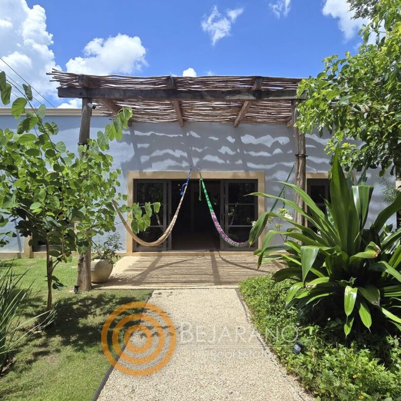 Andador entre jardín tropical hacia el porche con hamacas