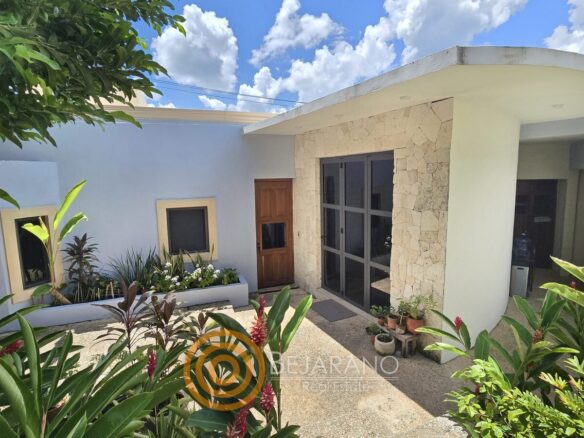 Fachada interior blanca con piedra y plantas tropicales