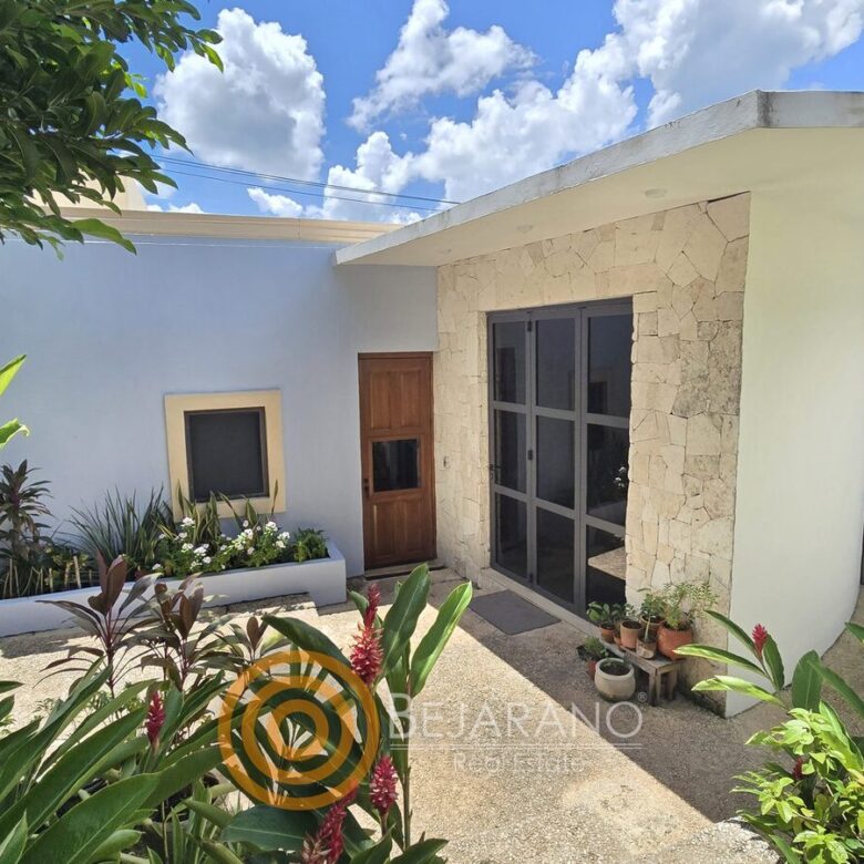 Fachada interior blanca con piedra y plantas tropicales