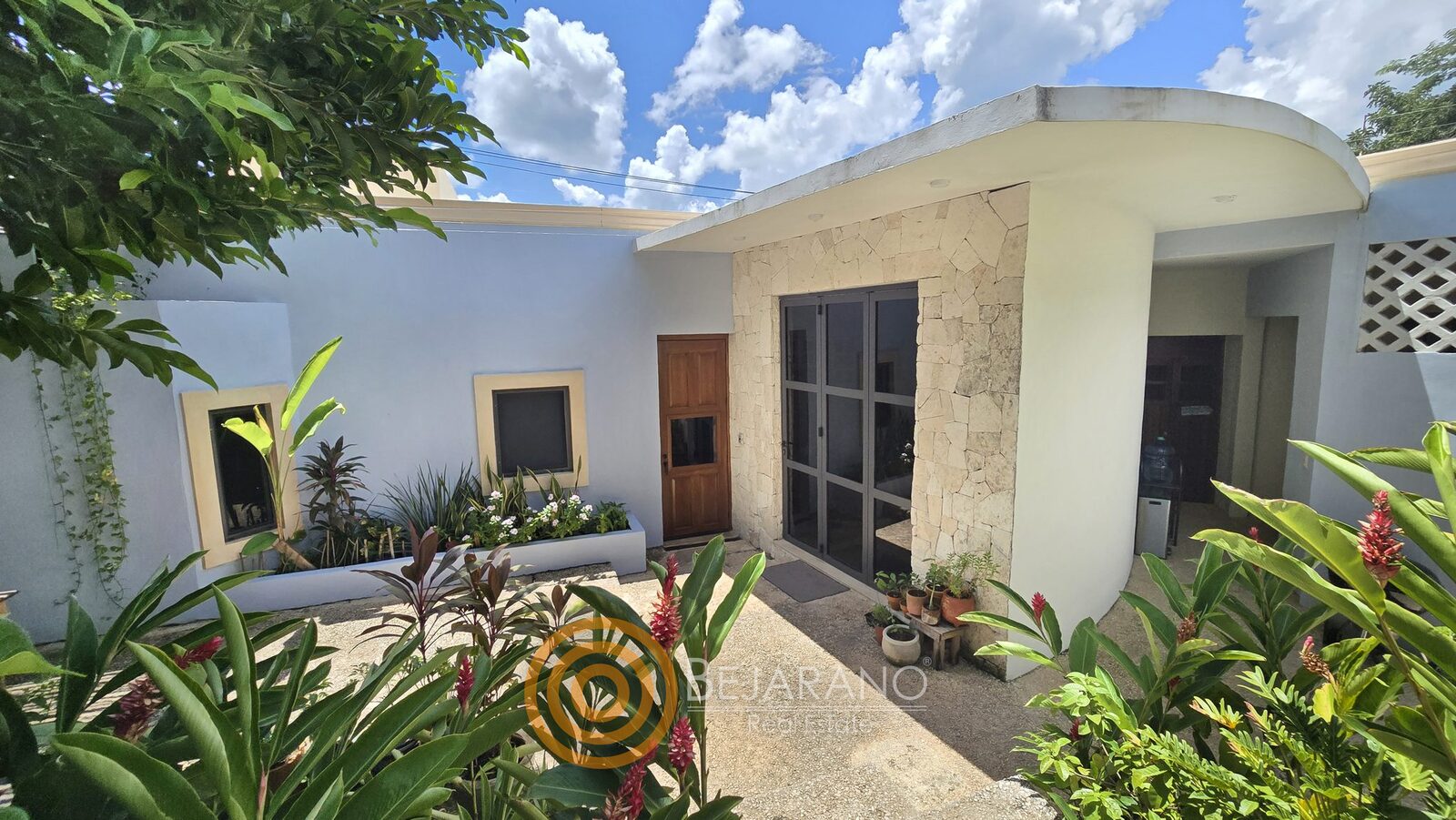bre-cv-petanka-08 Fachada interior blanca con piedra y plantas tropicales