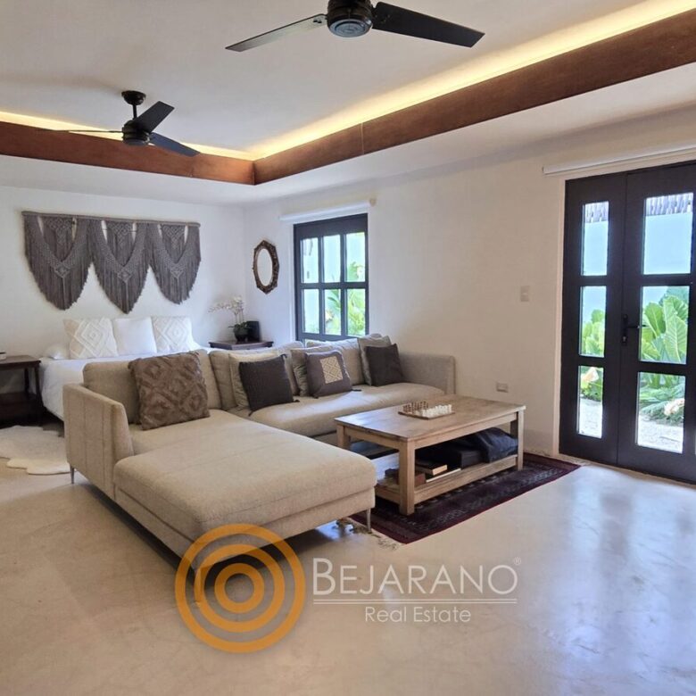 Sala con sofá esquinero, ventilador de techo y puertas al patio