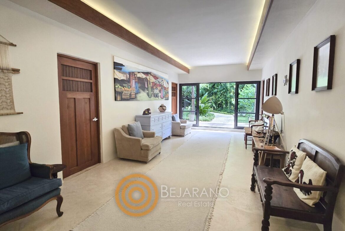 Estancia alargada con bancas de madera y ventanal al jardín
