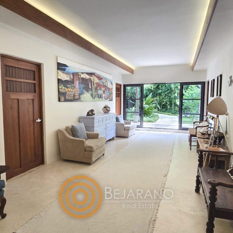 Estancia alargada con bancas de madera y ventanal al jardín