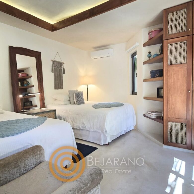 Recámara con dos camas, clóset de madera y ventana al jardín