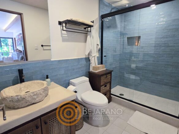 Baño con lavabo de piedra y regadera de azulejo azul
