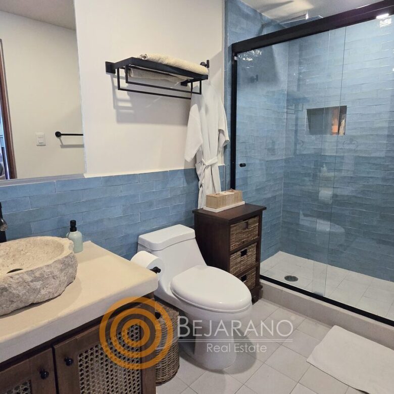 Baño con lavabo de piedra y regadera de azulejo azul