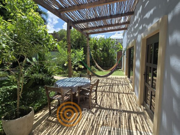 Corredor exterior con hamaca y comedor bajo pérgola de carrizo